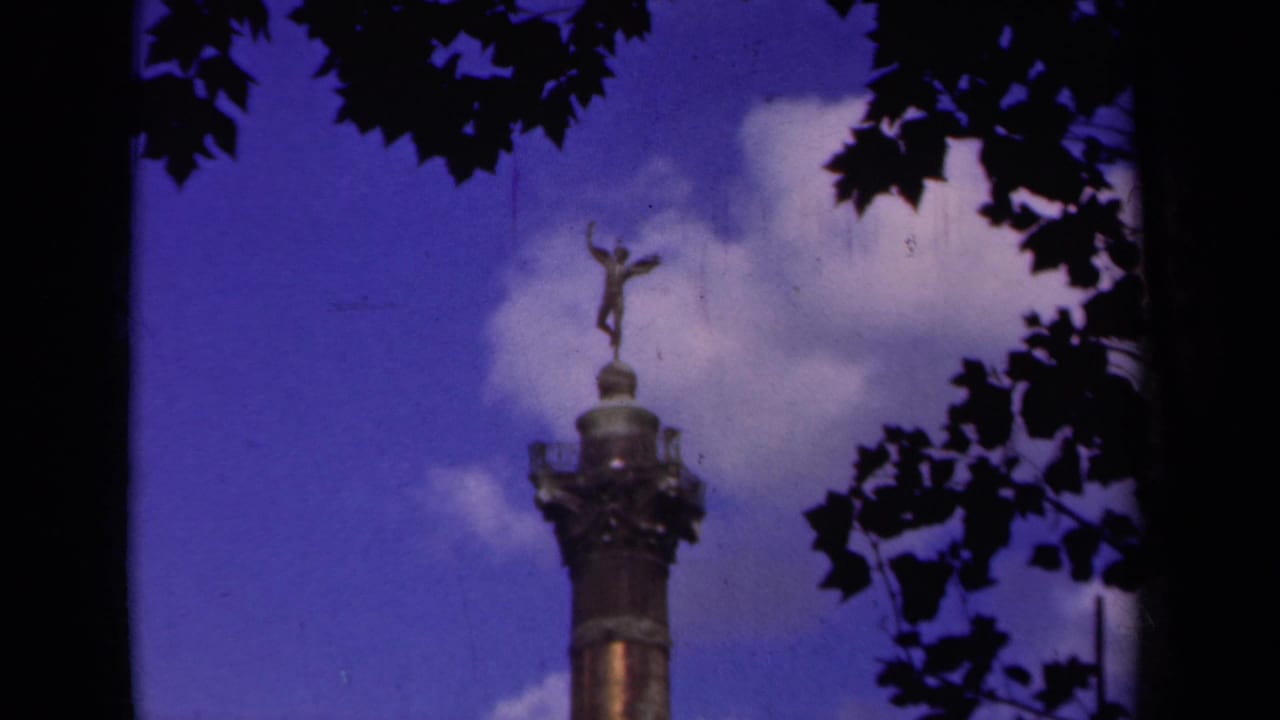 8mm Paris frame with the monument rising from the lower edge toward leaves and a bright cloud bank.