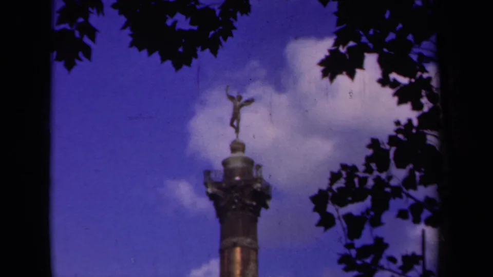 8mm Paris frame with the monument rising from the lower edge toward leaves and a bright cloud bank.