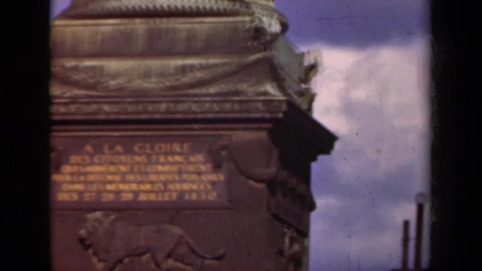 1939 Paris 8mm close-up of Arc de Triomphe inscription detail, with lion relief below and cloudy sky at the side.