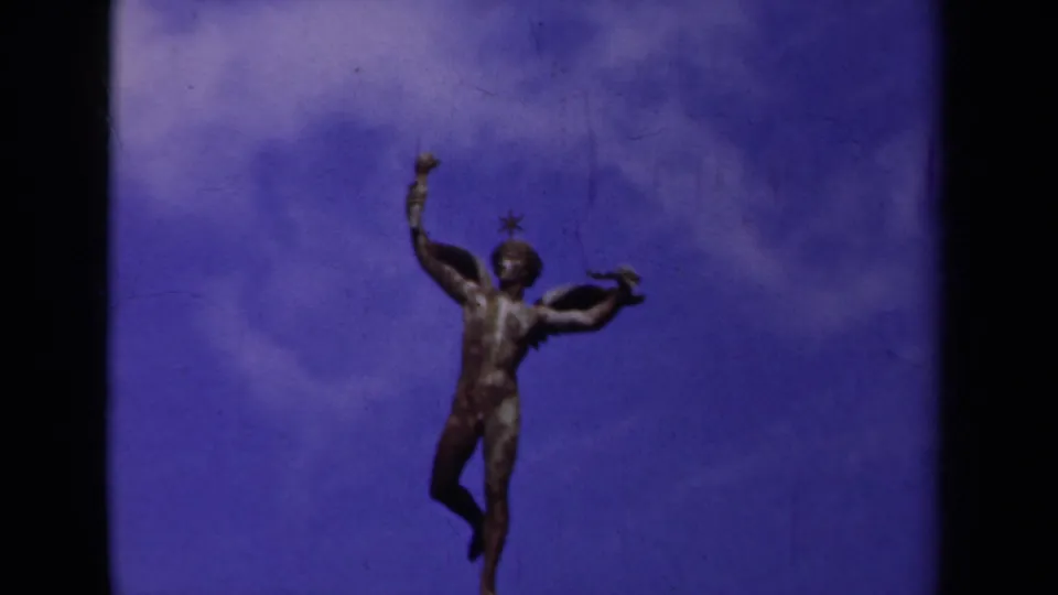 1939 Paris frame with the winged male statue held near center, one arm lifted above a cloudy blue sky.