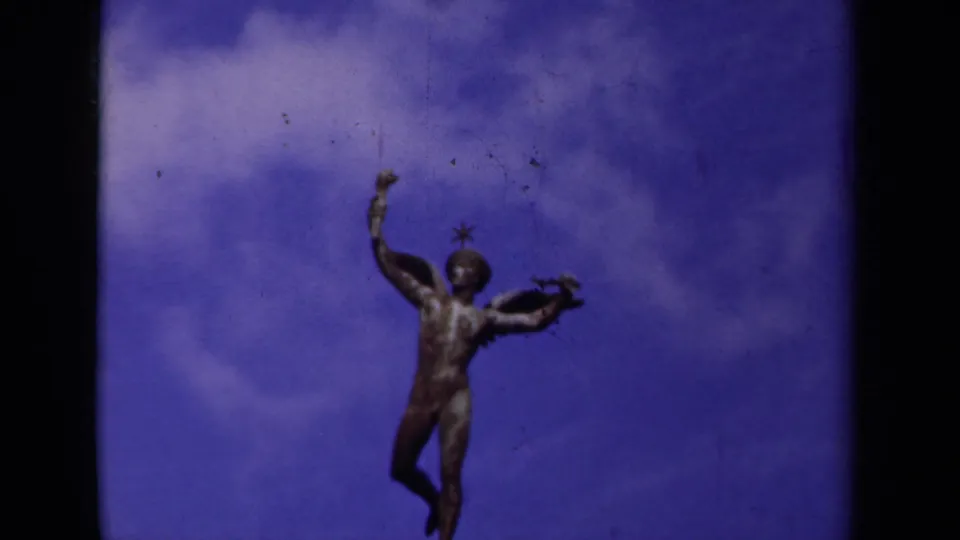 Final 1939 Paris frame showing the winged male statue silhouetted against saturated blue sky and pale clouds.