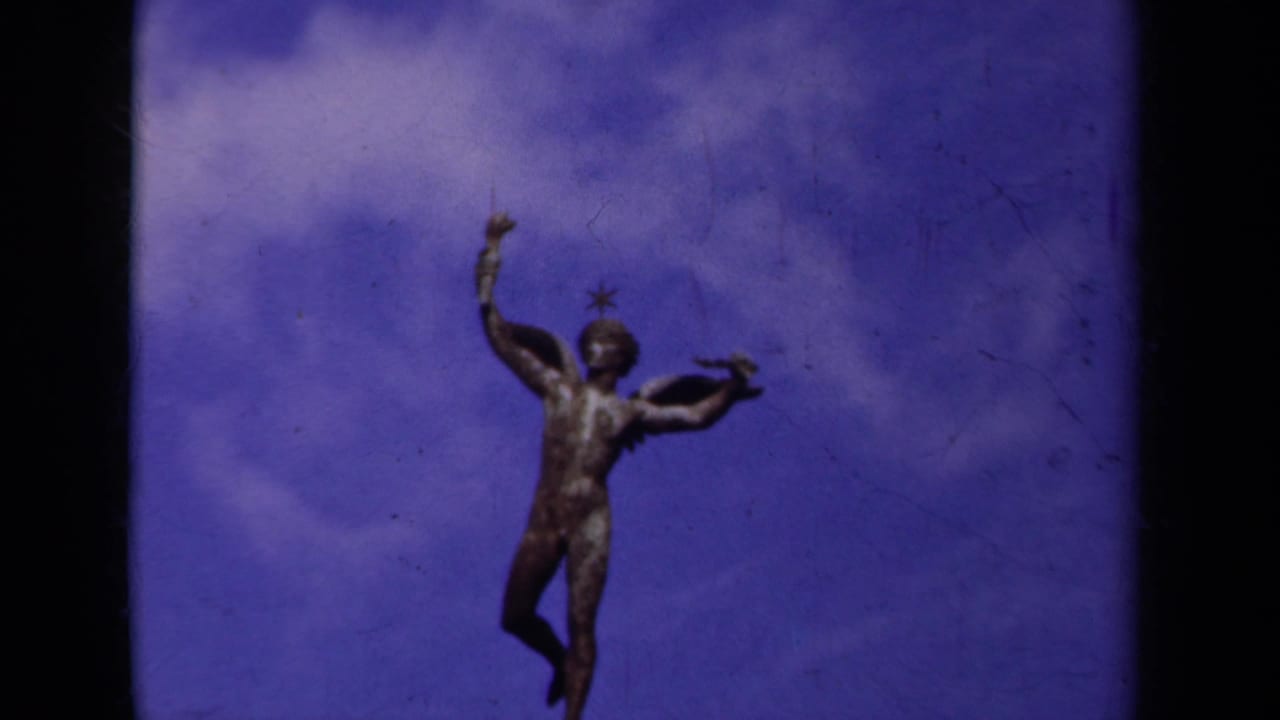 Winged nude statue above an arched bridge against a purple sky.