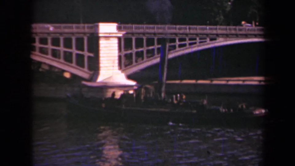 1939 Paris river scene with a bright bridge support, dark water, and a passenger barge moving beneath the arched structure.