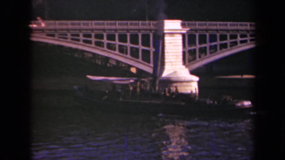 Paris river scene from 1939 showing smoke above an arched bridge and a small boat near the pier in soft 8mm color.