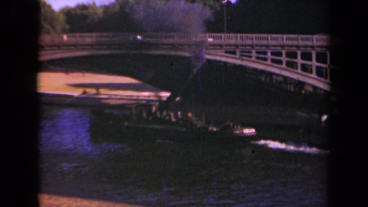 1939 Paris frame with the boat closer to the arched bridge, smoke rising and cars visible along the bridge deck.
