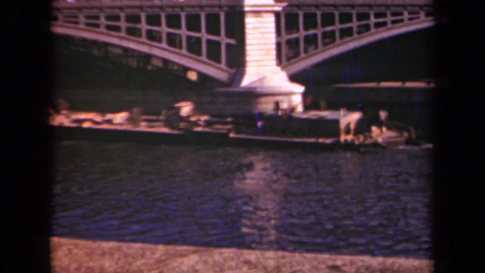 1939 Paris frame with a low river boat passing a bridge pier beneath an arched span.