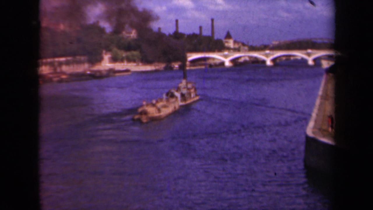 1939 Paris river traffic seen from the water, with a small barge heading toward an arched bridge.