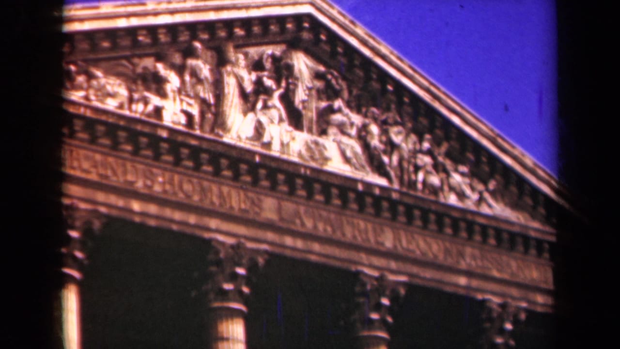 1939 Paris home-movie view of the upper facade of a neoclassical monument with a carved pediment, French inscription, and columns.