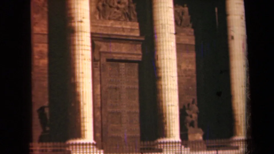 1939 Paris home-movie frame of the monument entrance with tall fluted columns, carved stonework, and a large central door.