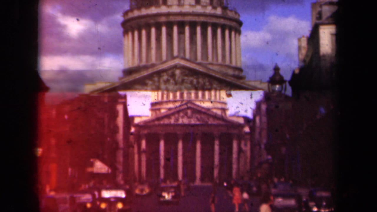 Panthéon facade and dome seen from a Paris street with cars and pedestrians.