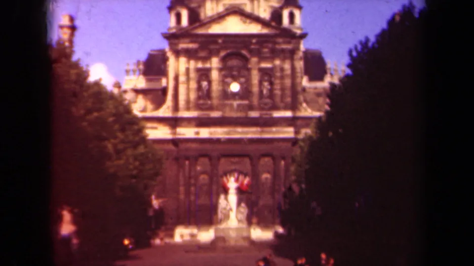 Paris 1939 home-movie frame of Hôtel des Invalides, with trees enclosing the view and pedestrians near the lower edge.