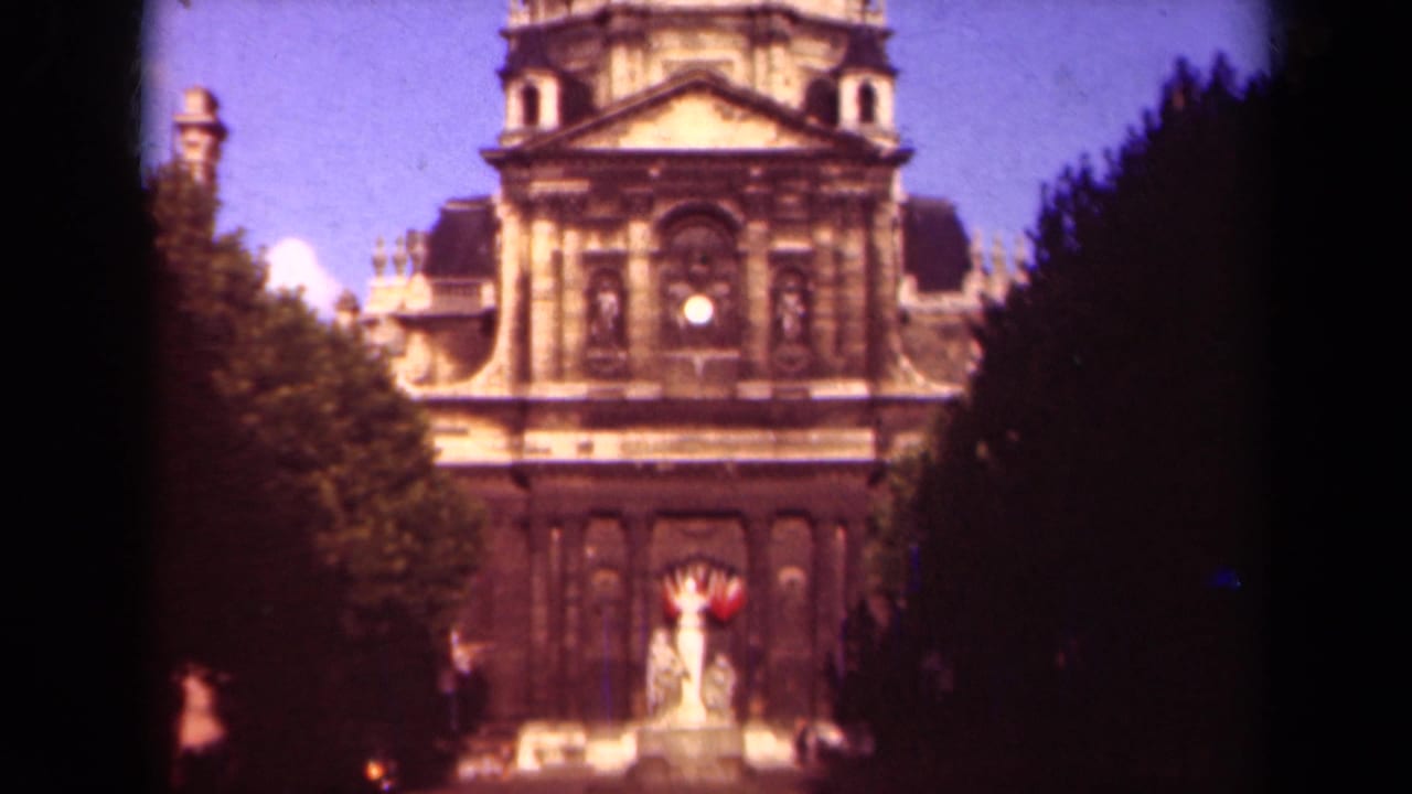 Domed stone building facade framed by trees, with tiny figures near the entrance.