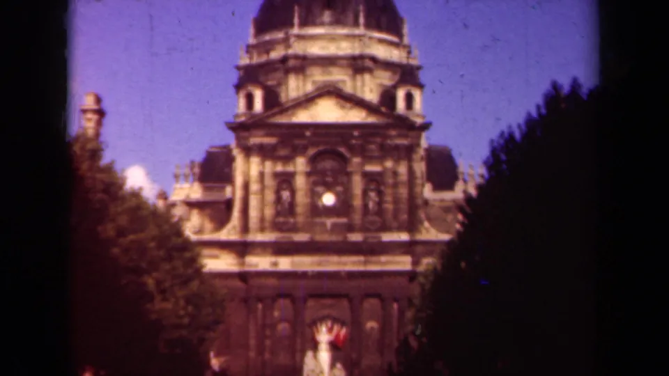 1939 Paris frame with a domed stone building centered between trees, the entrance area and small distant figures near the bottom.