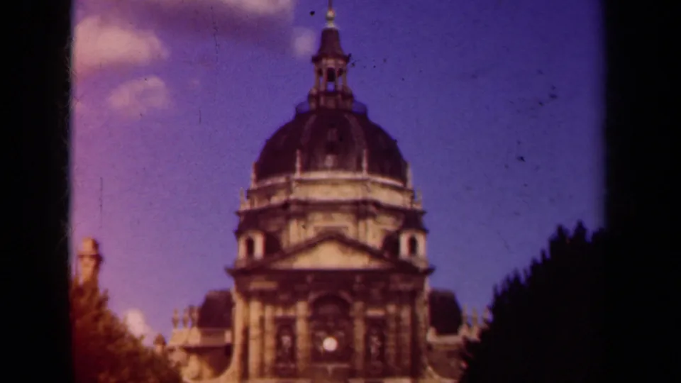 Late-1930s Paris frame showing the upper dome, pediment, and dark tree line as the camera completes its upward movement.