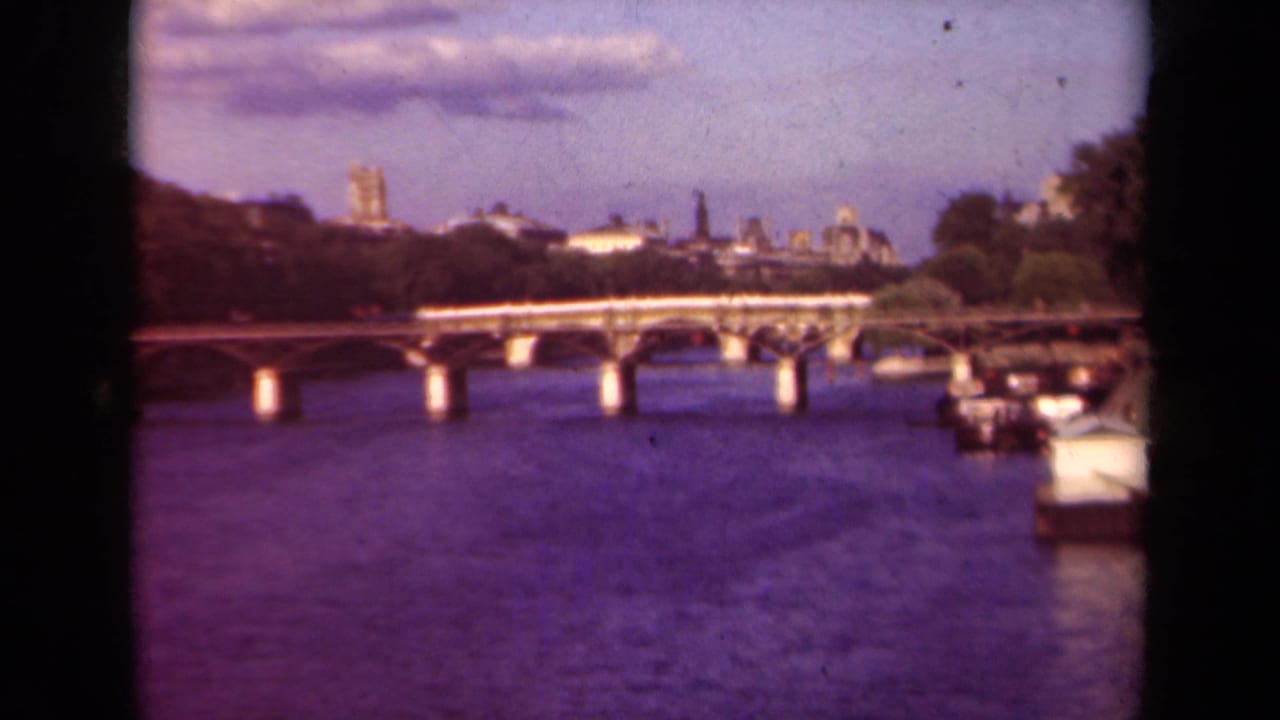 Stone bridge over the Seine with distant Paris skyline and cathedral towers.