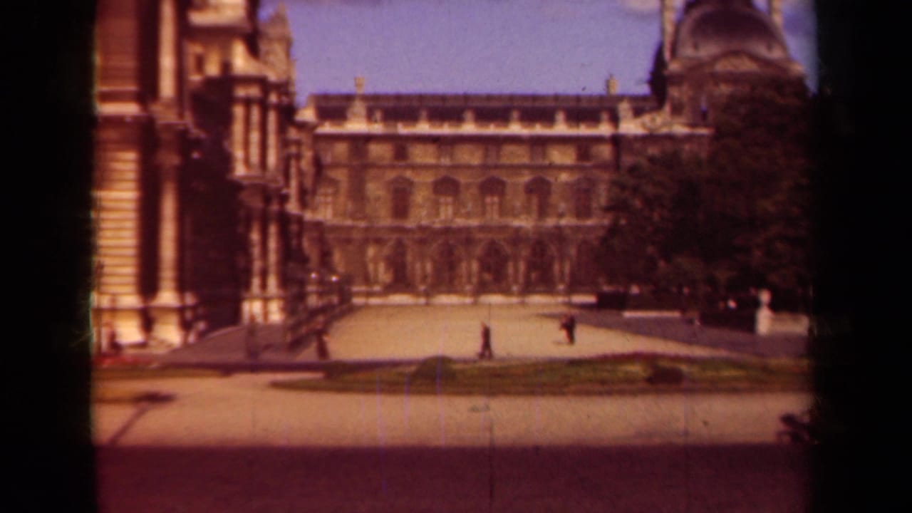 1939 Paris frame of the Louvre courtyard, with a formal facade, open paving, clipped garden beds, trees, and distant pedestrians.