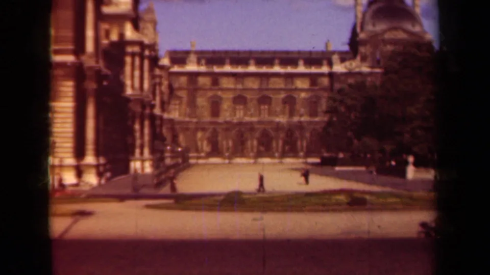 1939 Paris frame of the Louvre courtyard, with a formal facade, open paving, clipped garden beds, trees, and distant pedestrians.