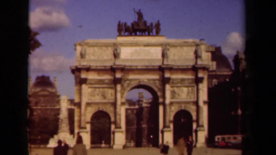 1939 Paris street-side landmark frame with a triumphal arch, visitors, and a red-and-white vehicle near the edge.