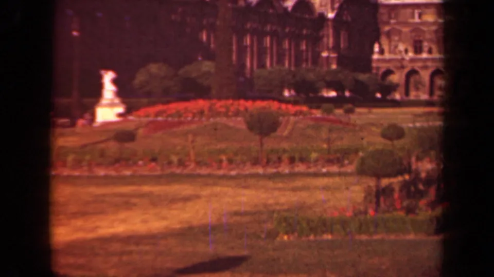 Paris garden and Louvre backdrop in faded 8mm color, with red flowerbeds, clipped shrubs, lawn, and a white statue.
