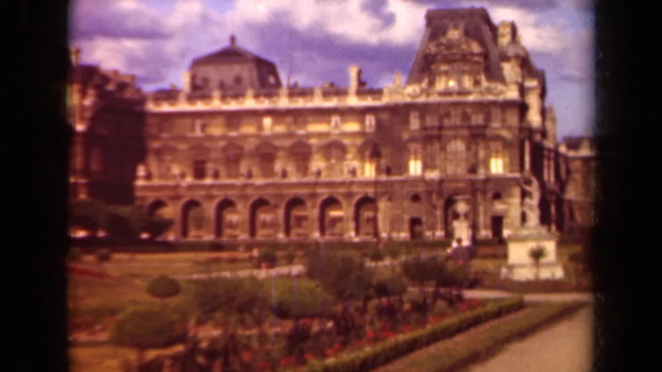 1939 Paris footage shows the Louvre facade, arched colonnade, garden beds, and a pale statue near the right edge.