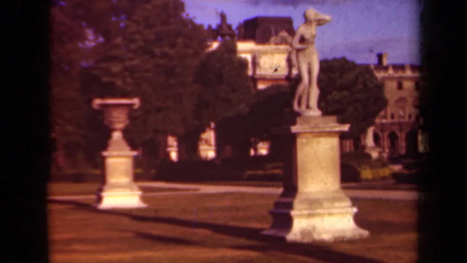 1939 Paris garden view near the Louvre, with a classical statue on a stone pedestal, urns, paths, trees, and palace architecture behind.