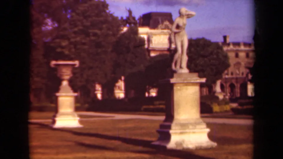 Final 1939 Paris frame holding on garden statuary and an urn against trees and a historic building.