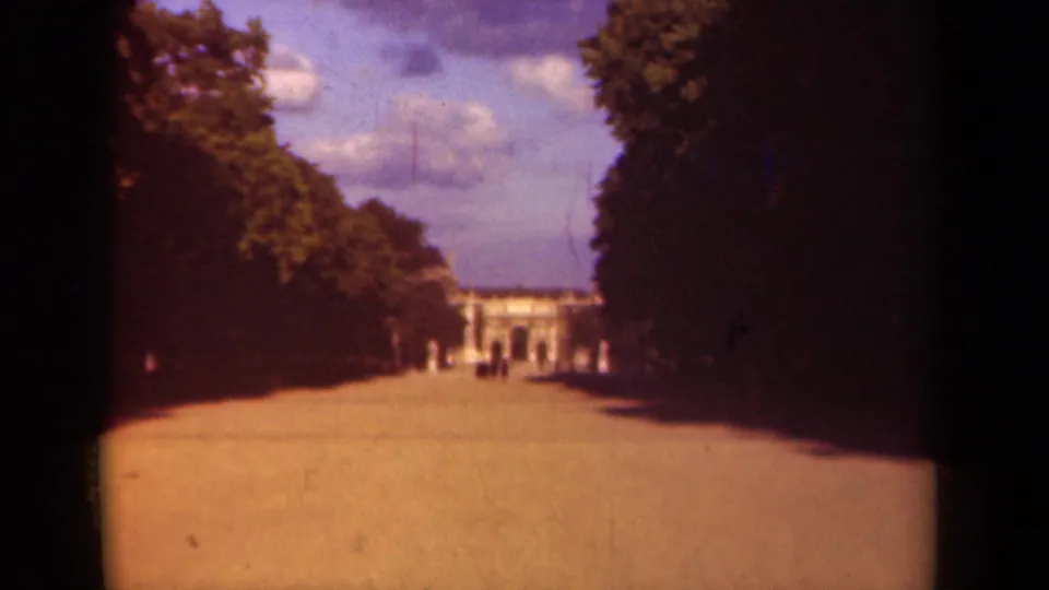 1939 Paris 8mm frame showing a broad park walk lined with trees and a distant classical building in soft color.