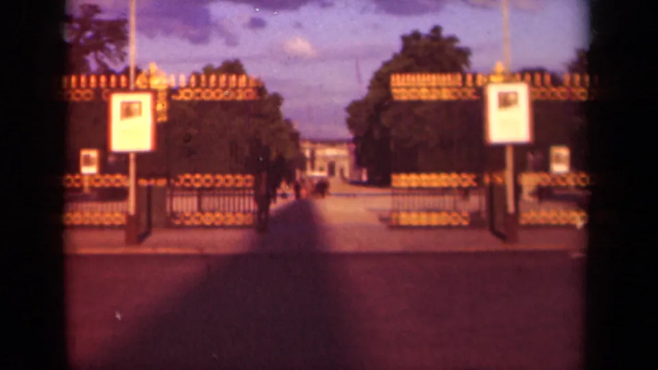 1939 Paris frame of a formal gated entrance with signs and trees, with indistinct pedestrians along the walkway.
