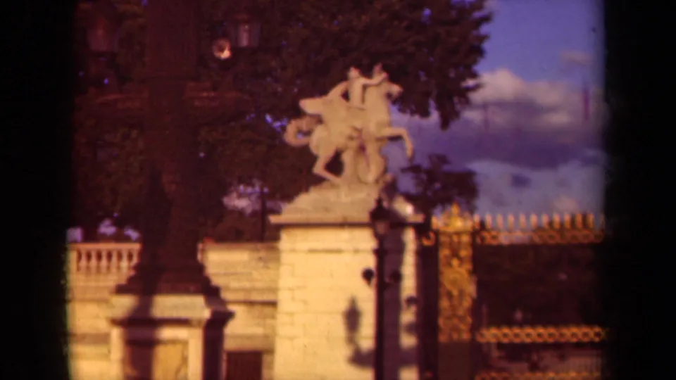 1939 Paris home-movie still showing the equestrian statue from a similar visitor angle, with fencework, trees, and sky visible.