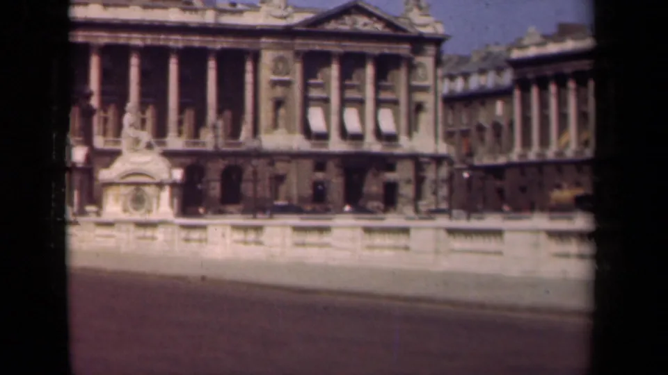 1939 Paris frame showing a monumental neoclassical facade, adjoining building wing, stone railing, and open street.