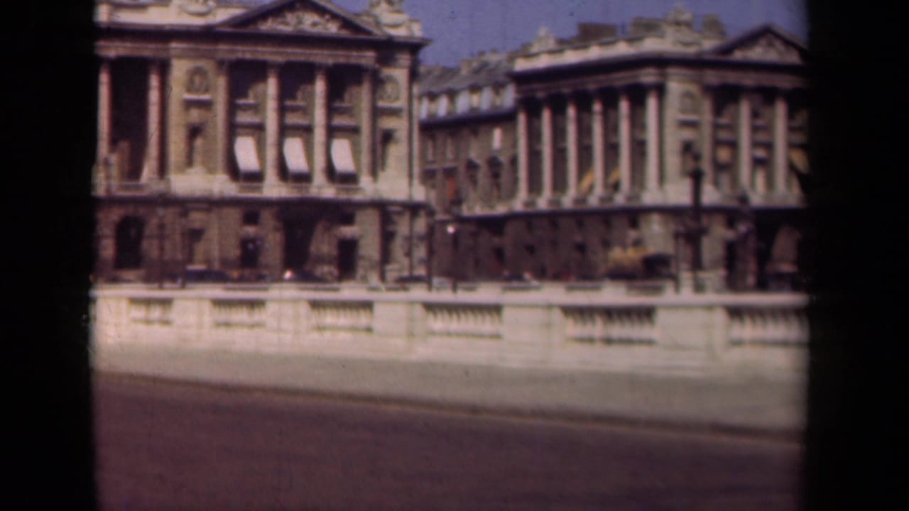 1939 Paris frame with a sunlit colonnaded facade, stone balustrade, roadway, and visible 8mm film-frame borders.