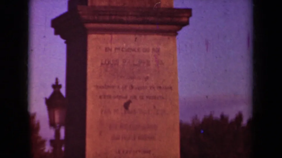 End frame of the 1939 Paris monument view, with inscription detail, ornate lamp, trees, and visible 8mm frame border.