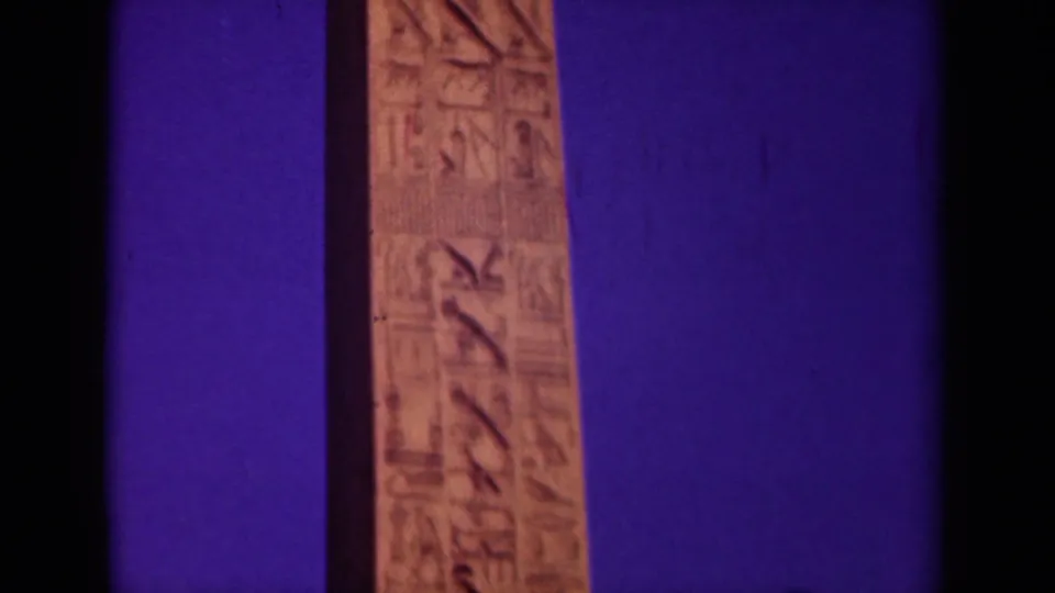 1939 Paris home-movie frame showing a lower section of the obelisk shaft with carved markings, soft focus, and visible film grain.