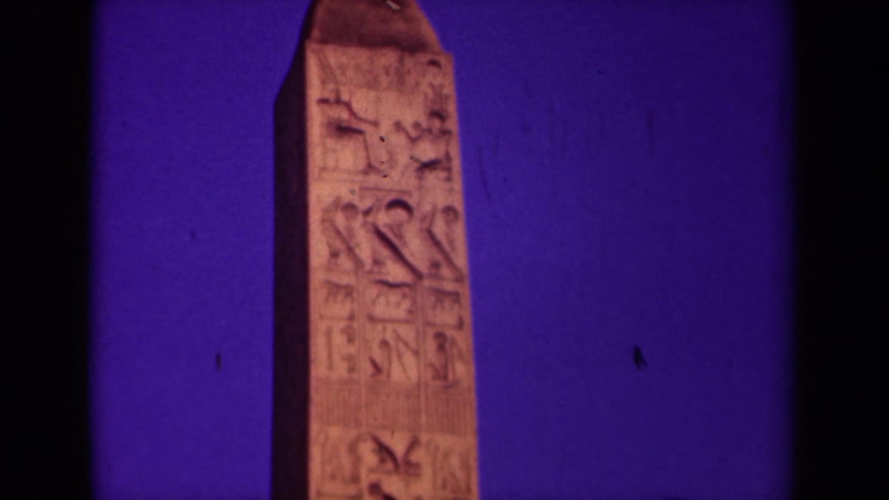 Close 1939 Paris home-movie view of an obelisk with carved markings, framed tightly against a saturated dusk sky.