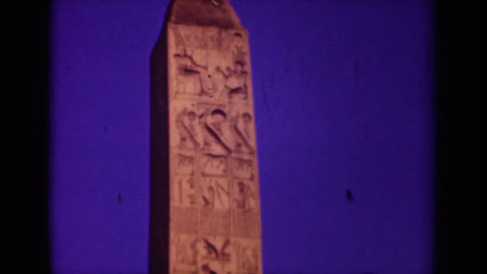 Close 1939 Paris home-movie view of an obelisk with carved markings, framed tightly against a saturated dusk sky.