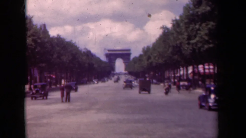 1939 Paris home-movie view down the Champs-Elysees, showing the Arc de Triomphe, moving cars, pedestrians, and visible 8mm frame borders.