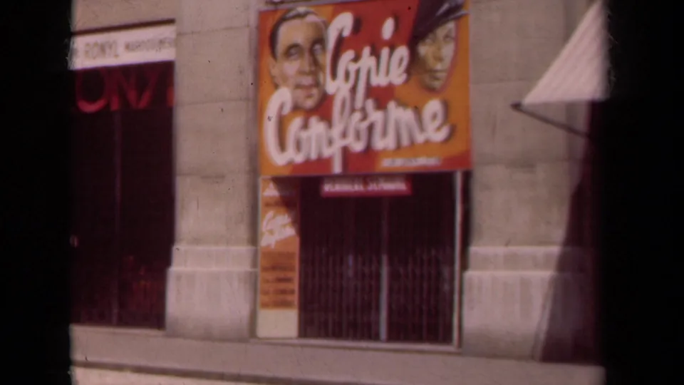 1939 Paris frame with dark film-edge bands around a cinema facade, orange poster artwork, red doorway, and pale stone columns.