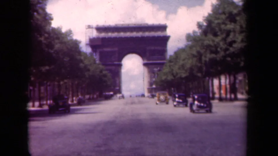 Paris avenue view toward the Arc de Triomphe, with late-1930s cars on the roadway and rows of trees framing the street.