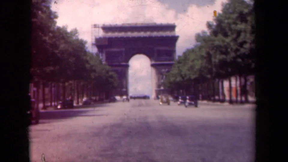 1939 Paris 8mm frame showing the Arc de Triomphe, a tree-lined Champs-Elysees view, and small cars on the road.