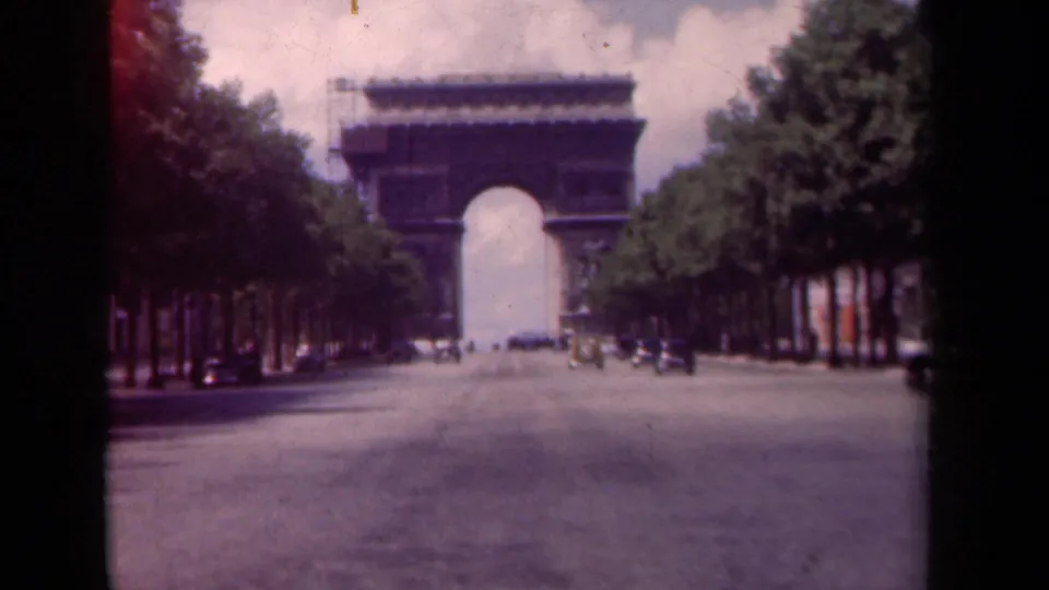 1939 Paris frame of the Arc de Triomphe from the Champs-Elysees, with period cars, trees, and visible 8mm film edges.