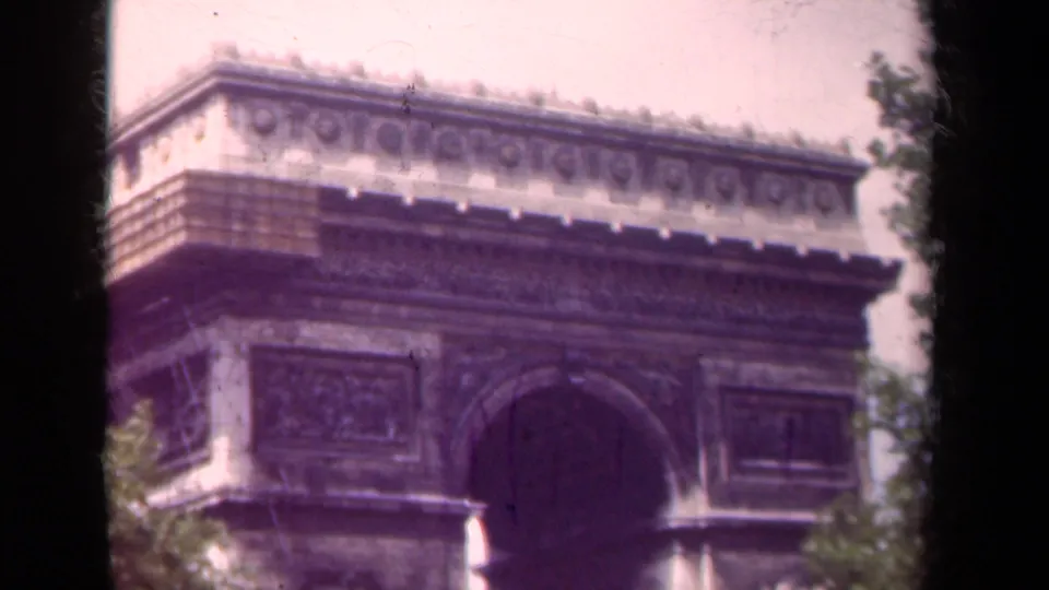 The Arc de Triomphe in Paris appears in soft color 8mm footage with trees and dark film edges visible.