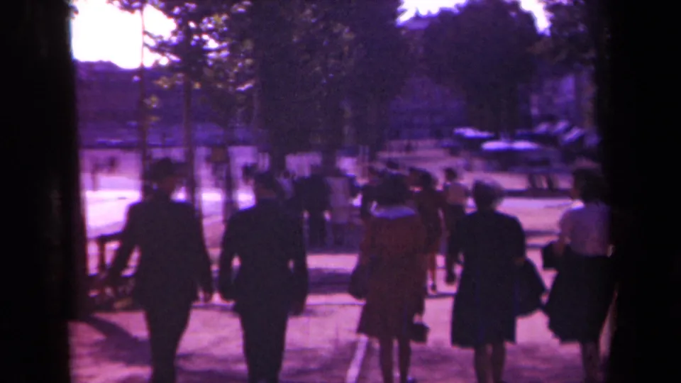 Final 1939 Paris boulevard frame showing adults walking away from the camera amid trees, distant cars, and faded 8mm color.