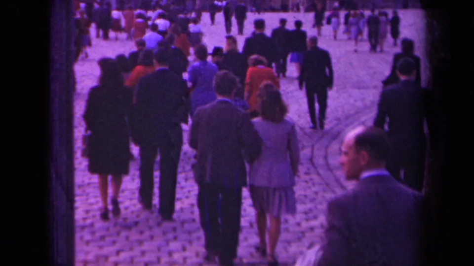 1939 Paris street footage showing pedestrians from behind on cobblestones, including suited men and women in dresses.
