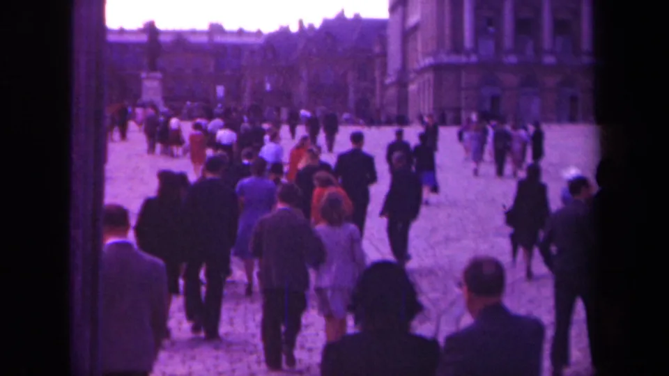 Paris 1939 8mm frame showing a busy cobblestone square with pedestrians and surrounding stone architecture.