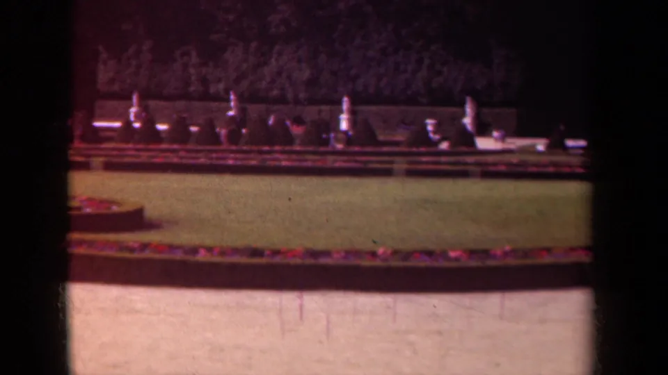 Final 1939 Paris frame shows the garden lawn and long flower border, with pale stone ornaments set against a dark hedge.