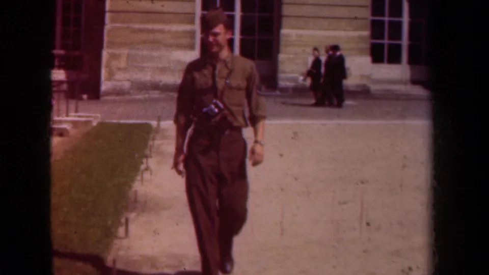 A closer 1939 Paris home-movie view shows the uniformed soldier walking toward the lens with his camera visible on his chest.