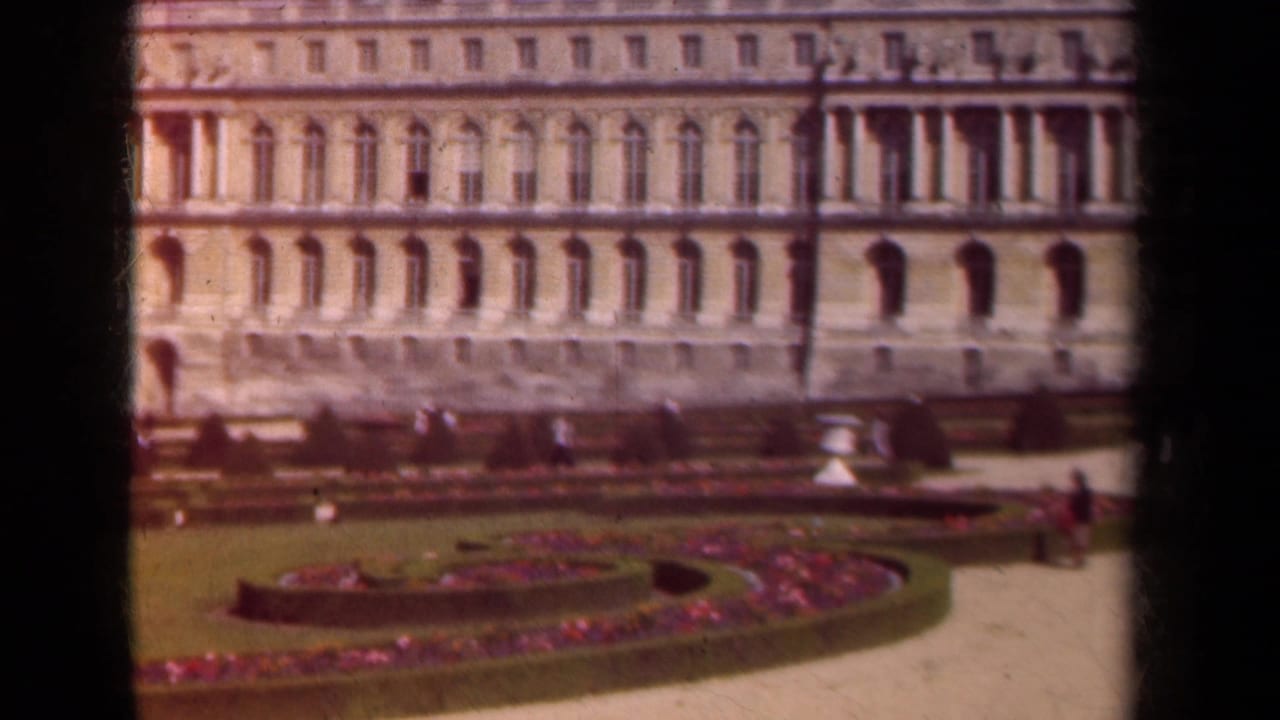 Formal garden and ornate facade with a few distant visitors near the path.