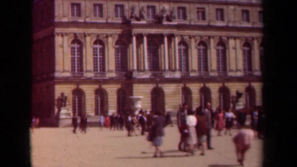1939 Paris home-movie frame of visitors gathered near a grand stone palace exterior with tall arched windows.