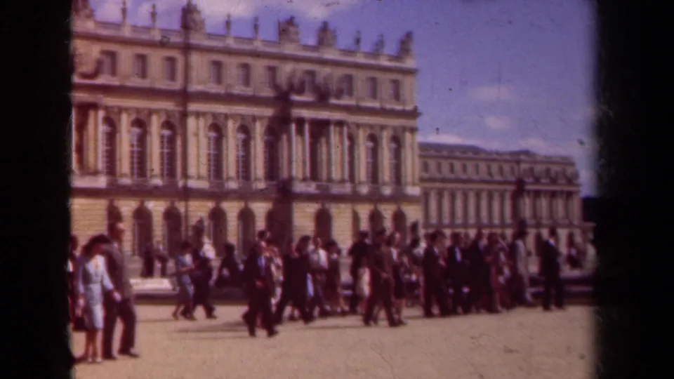 1939 Paris travel footage shows a group of tourists crossing a broad courtyard in front of a grand classical palace facade.