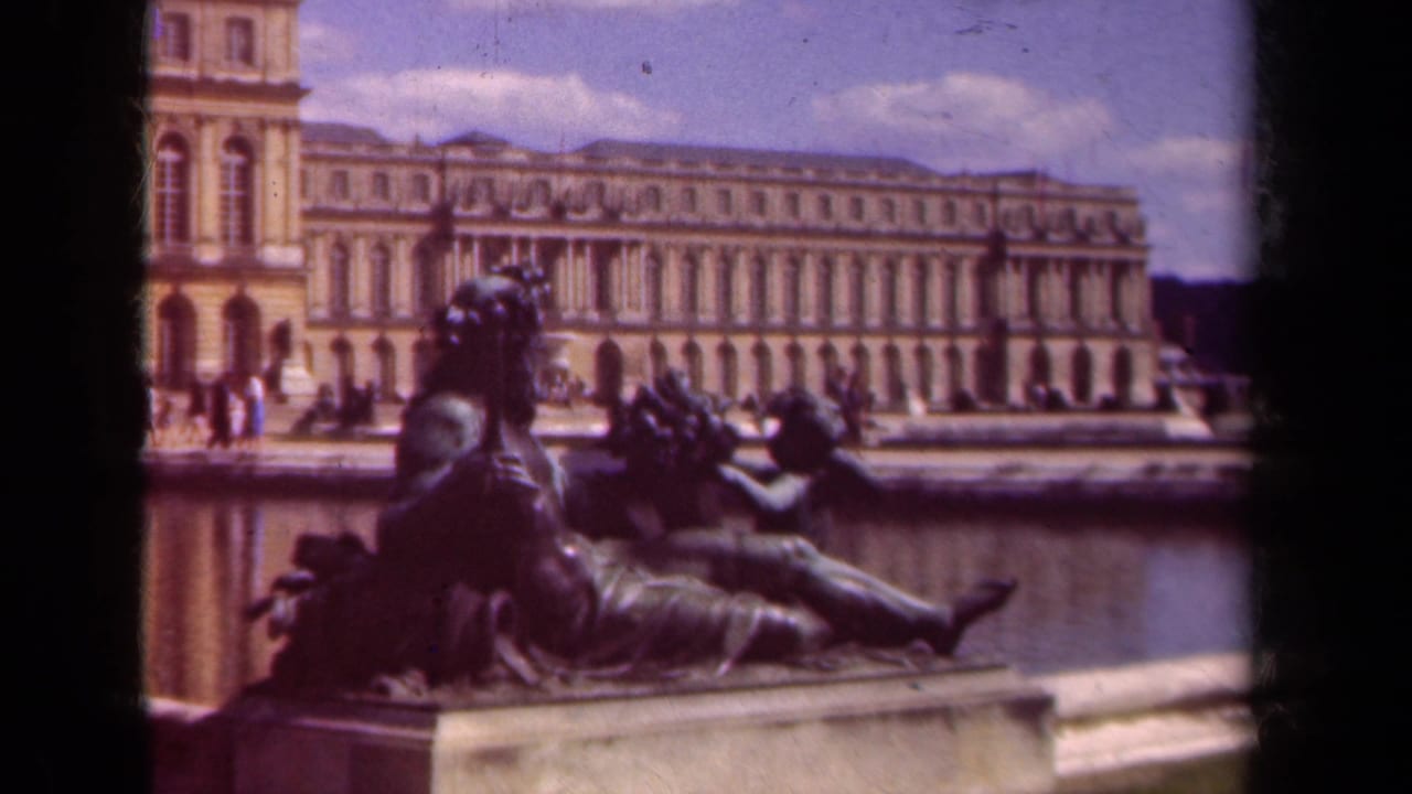 Bronze reclining statue beside a reflecting pool with a grand palace facade in the background.